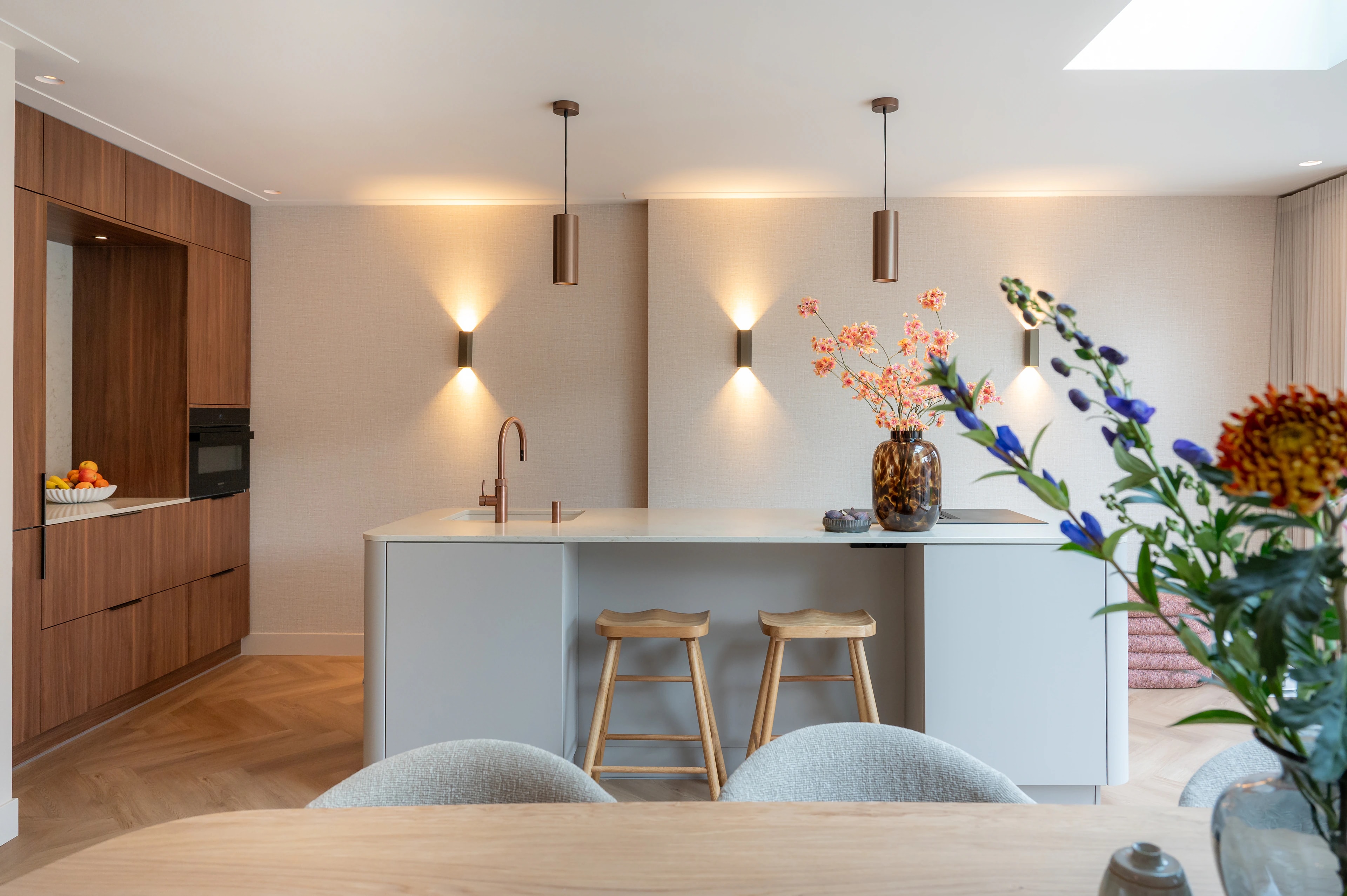Lichte keuken met kookeiland, houten kasten en warme verlichting
