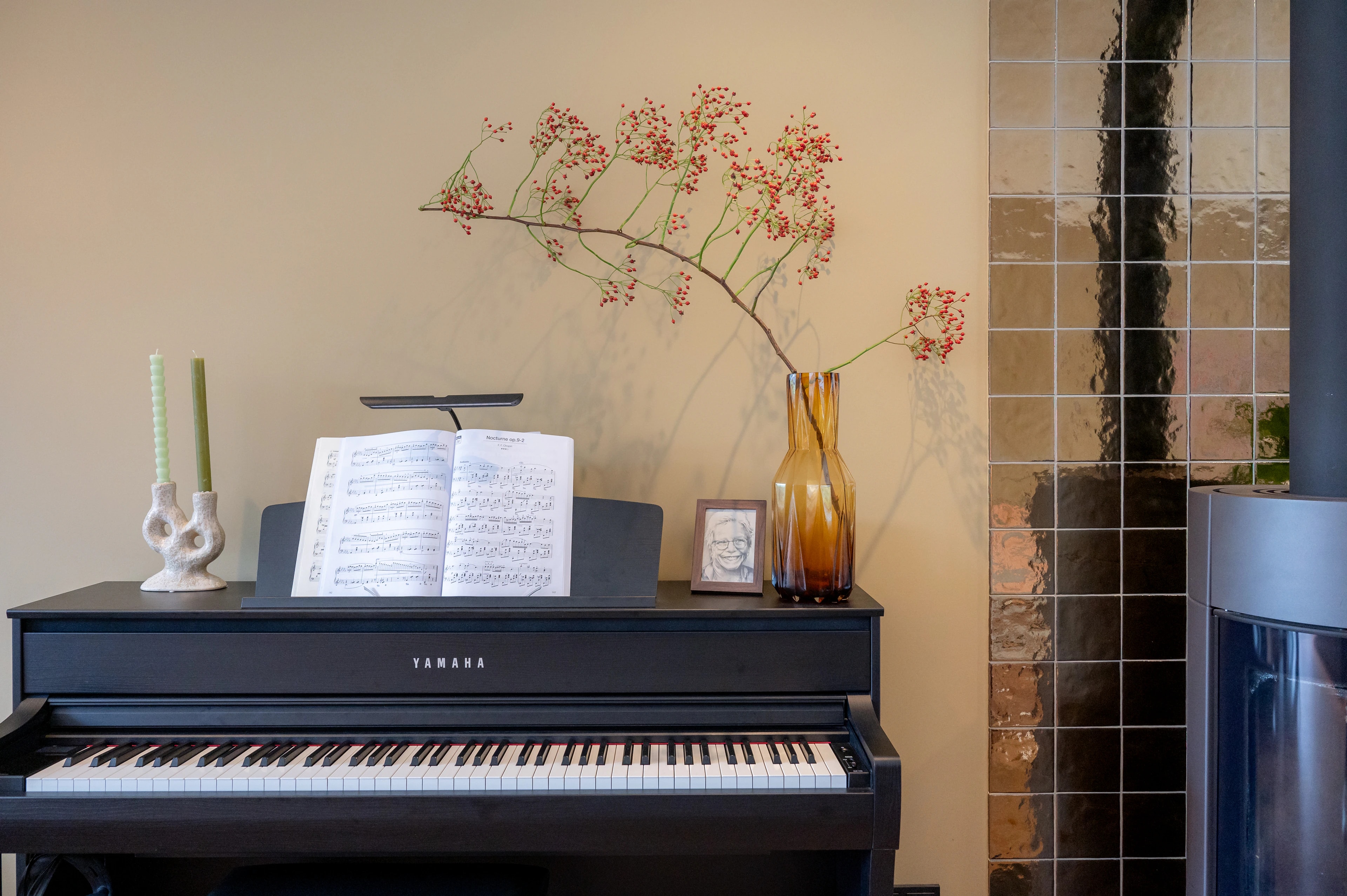 Piano met vaas en kunst naast de glanzende tegelwand